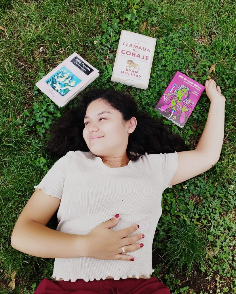 En el pasto, con tres libros de colores